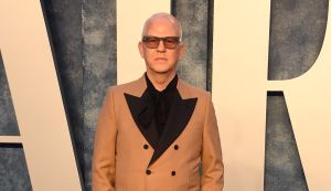 Ryan Murphy poses wearing a beige suit.