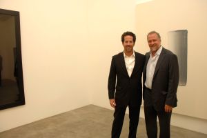 Two men dressed in suits pose in corner of art gallery