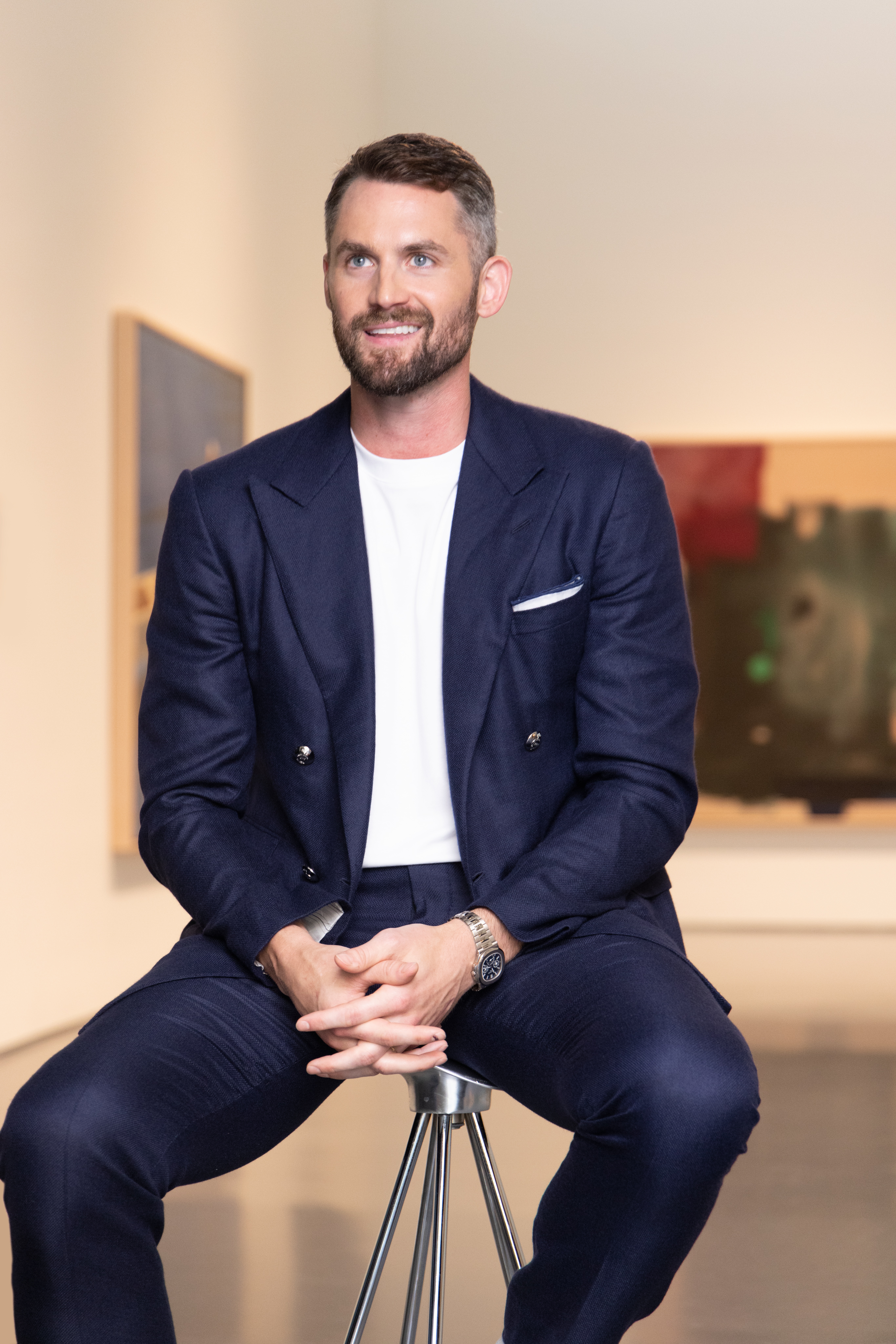 A man sits in a gallery space in front of an artwork