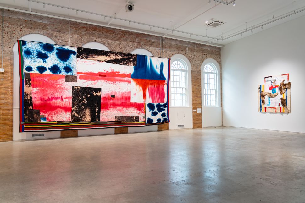 Installation view with a large colorful painting and a smaller assemblage on the wall.