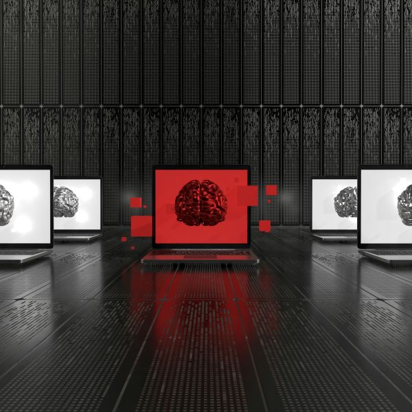 A row of laptops in a dark server room, with one central screen glowing red and displaying a 3D brain, symbolizing the rise of autonomous A.I. decision-making.
