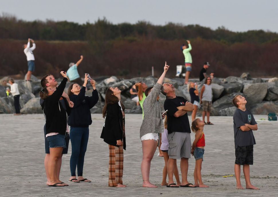 A group of people looking up on a beach.